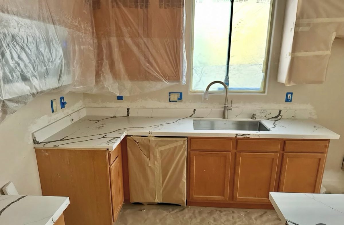 Kitchen countertop resurfaced with a white marble-look finish, surrounding area fully masked